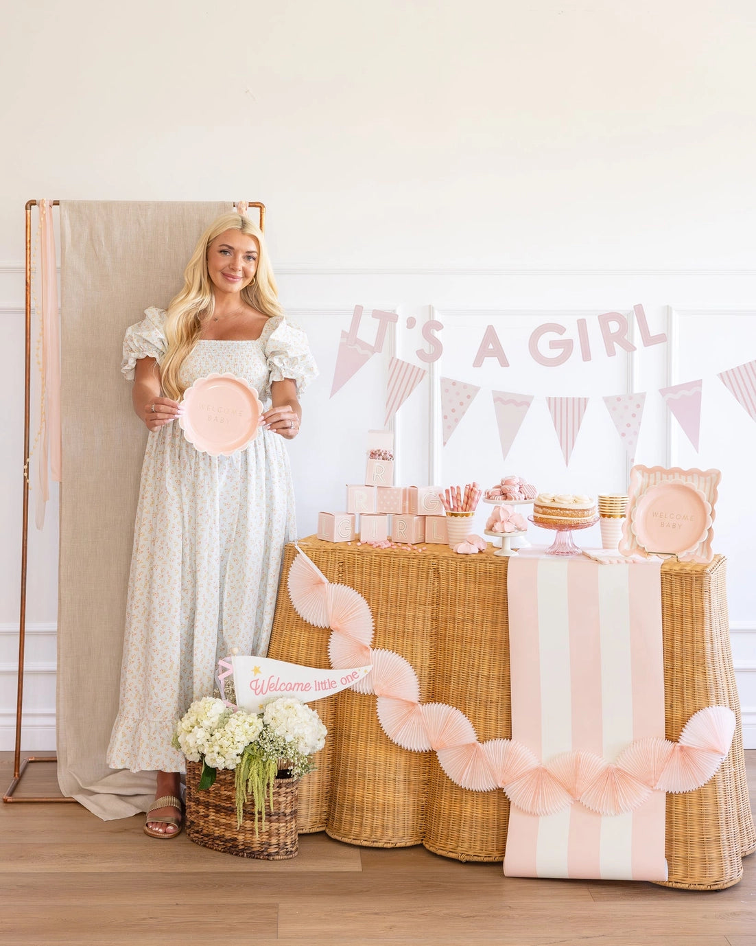 Woman holding a baby shower plate with 'It's a Girl' banner and decorations.