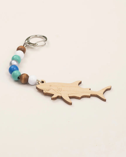 Wooden shark keychain with colorful beads on a beige background