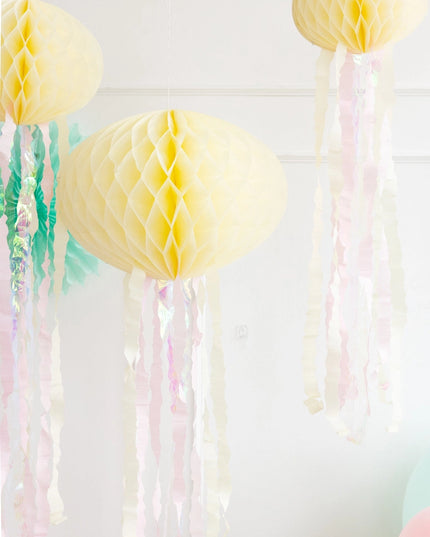 Decorative yellow honeycomb balls with streamers on a white background