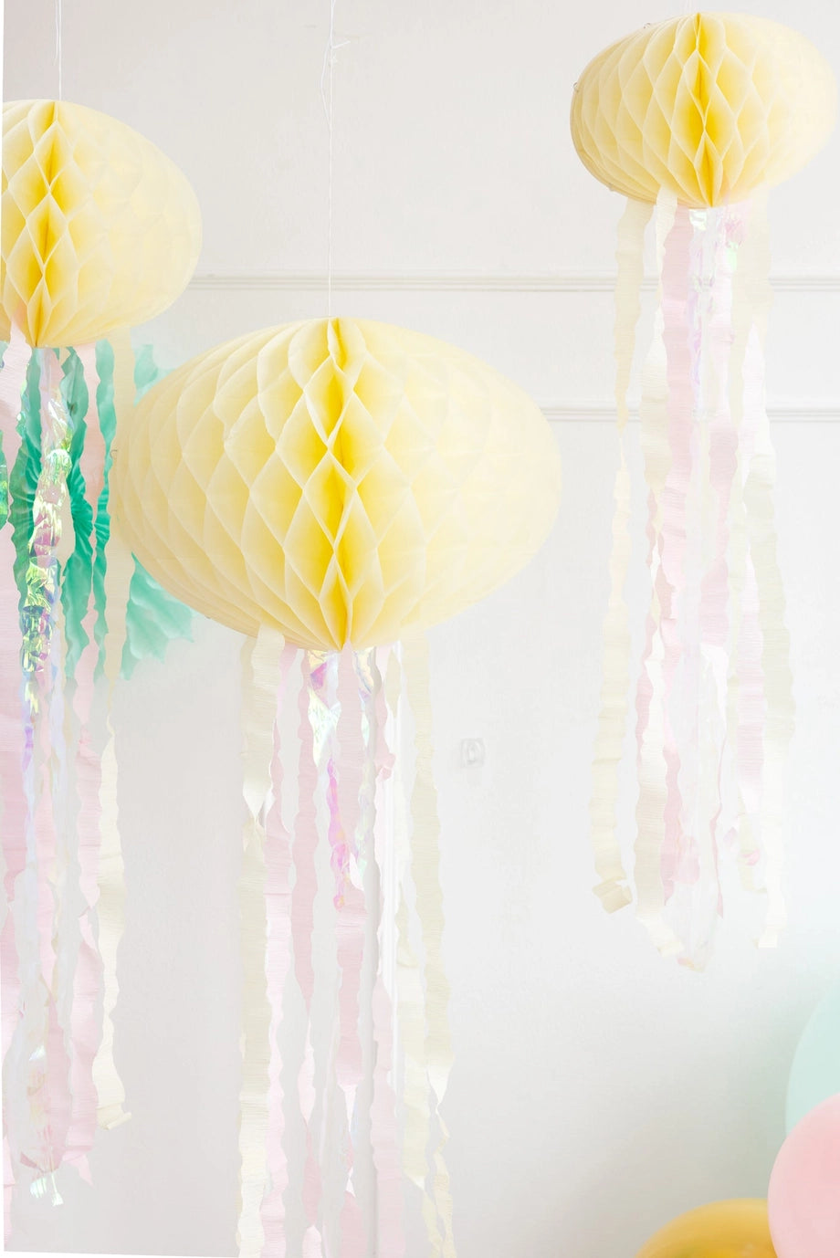 Decorative yellow honeycomb balls with streamers on a white background