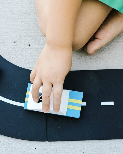 Child playing with toy cars on a road mat