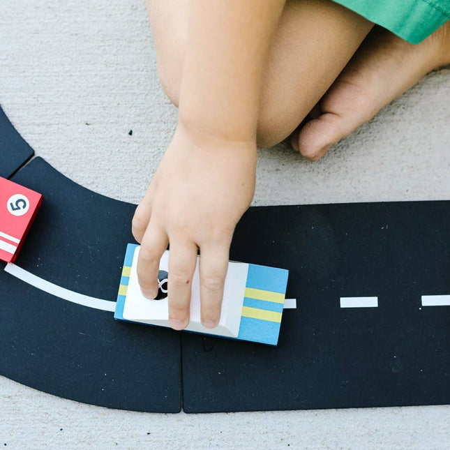 Child playing with toy cars on a road mat