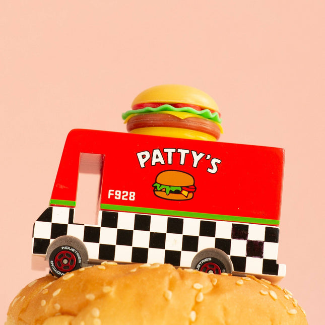 Toy truck labeled 'Patty's' with a hamburger on top of a bun against a pink background