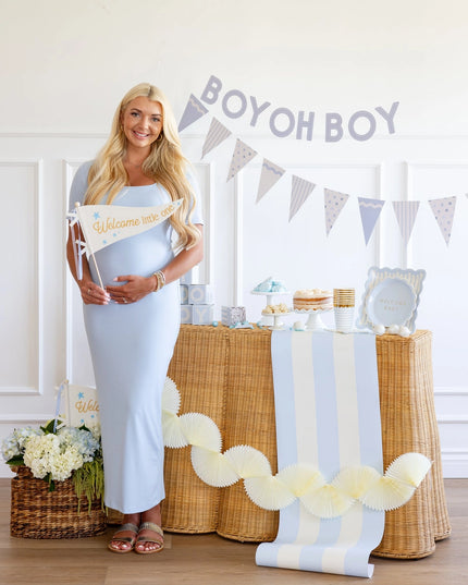 Pregnant woman standing next to a decorated table with 'Boy oh Boy' banner