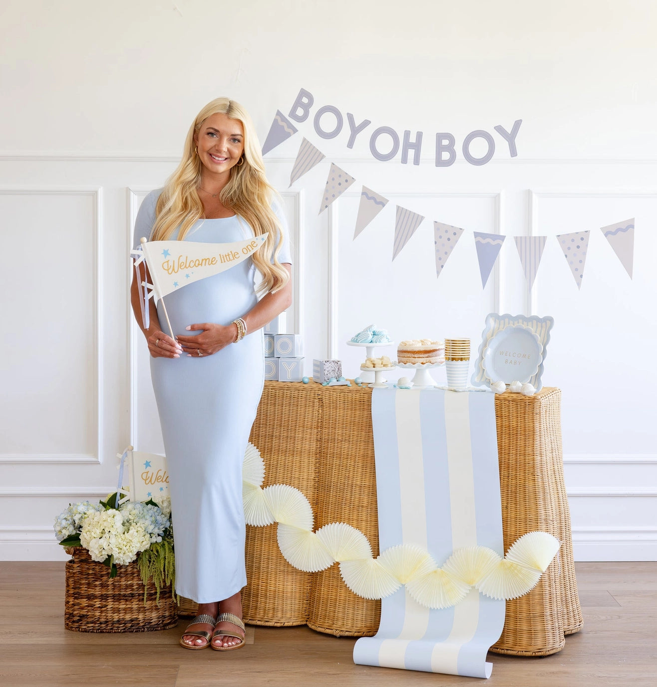 Pregnant woman standing next to a decorated table with 'Boy oh Boy' banner