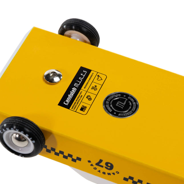 Yellow metal block with wheels and a label on a white background