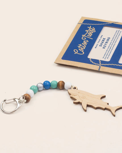 Shark keychain with beaded strap and packaging on a beige background