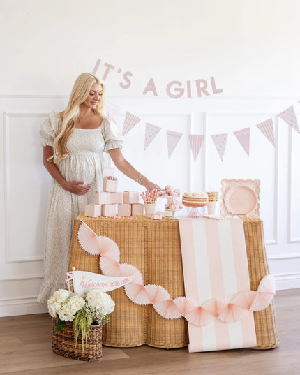 Woman standing next to a decorated table with 'It's a Girl' banner