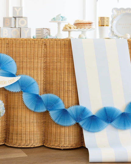 Decorative blue streamer with 'Welcome' sign on a table with floral arrangement and wicker baskets.