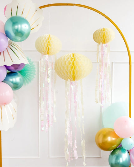 Decorative arch with colorful balloons and tassels against a white wall