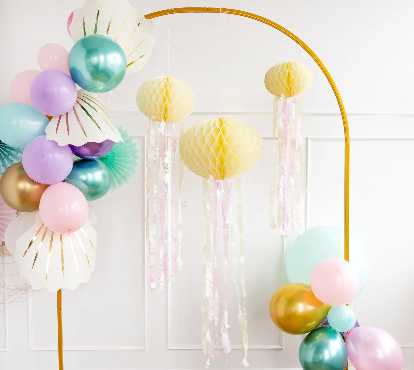 Decorative arch with colorful balloons and tassels against a white wall