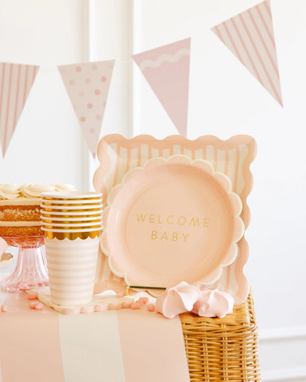 Decorative setup with 'Welcome Baby' plates and pink and gold accents.