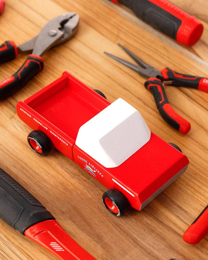 Red truck toy with tools on a wooden surface
