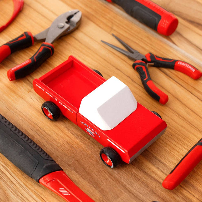 Red truck toy with tools on a wooden surface