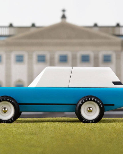 Model car on grass with a large building in the background