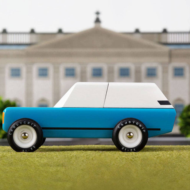 Model car on grass with a large building in the background