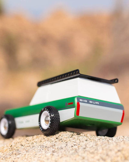 Toy lawn mower on sand with blurred natural background