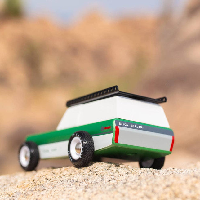 Toy lawn mower on sand with blurred natural background