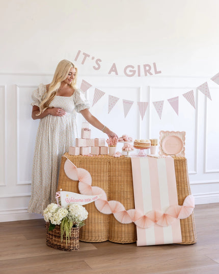 Woman standing next to a decorated table with 'It's a Girl' banner
