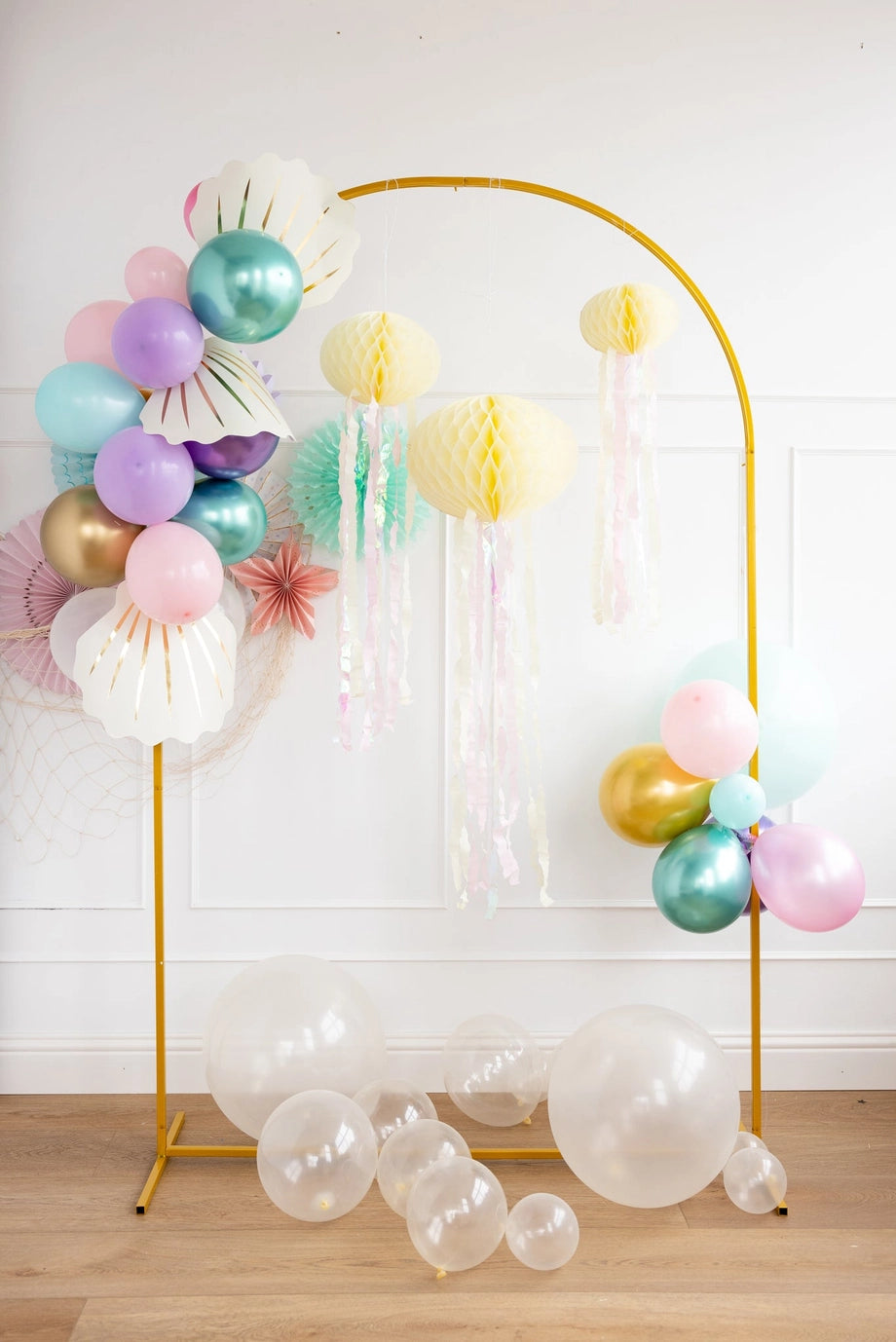 Decorative arch with colorful balloons and paper lanterns on a wooden floor.