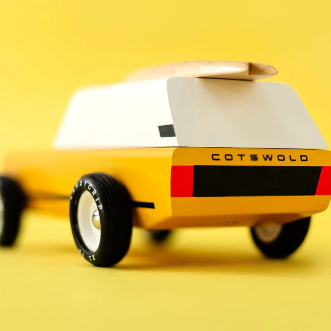Yellow toy car with white top and 'Cotswold' branding on a yellow background