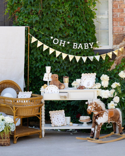 Baby shower setup with baby items, rocking horse, and 'OH BABY' banner.