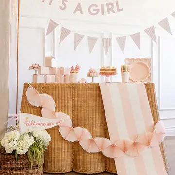 Baby shower setup with 'It's a Girl' banner, cake, and decorations.