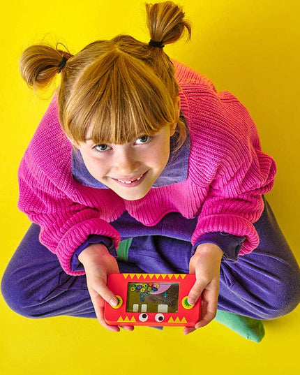 Child holding a small electronic device with a colorful screen against a yellow background