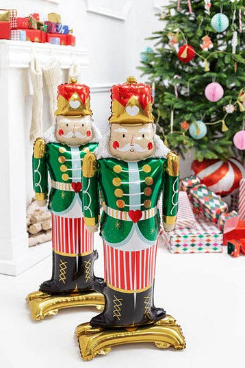 Decorative nutcrackers in festive attire with a Christmas tree and presents in the background.
