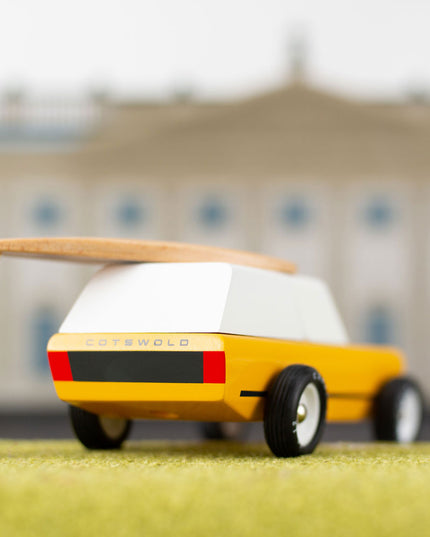 Toy figure directing a toy car with a blurred building in the background