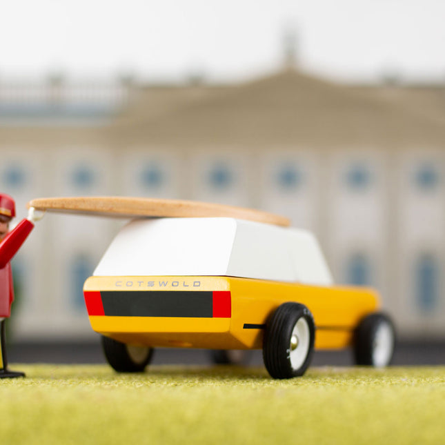 Toy figure directing a toy car with a blurred building in the background
