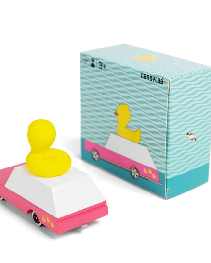 Yellow duck on a pink car with a blue box on a white background