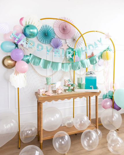 Birthday party setup with balloons, garlands, and a dessert table.