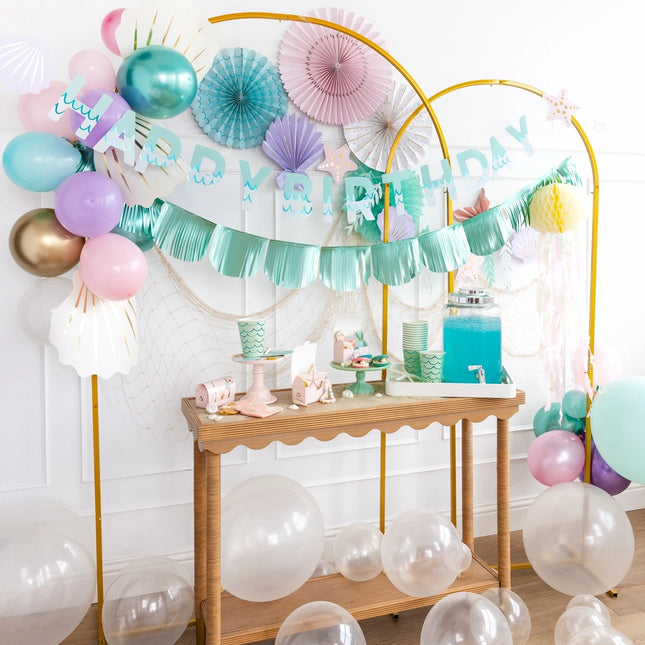 Birthday party setup with balloons, garlands, and a dessert table.