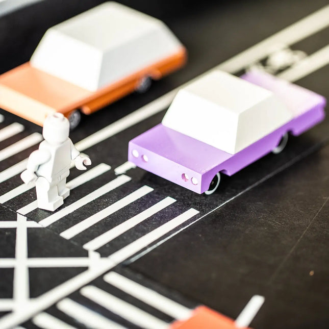 Small toy cars on a track with a white figure nearby