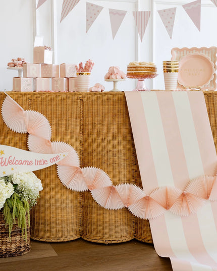 Decorated table with baby shower elements including a cake, balloons, and a 'Welcome little one' sign.