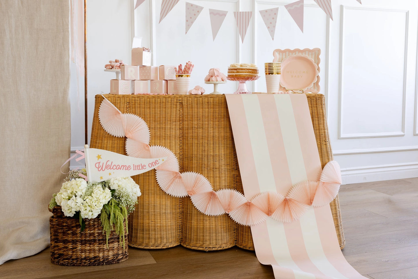 Decorated table with baby shower elements including a cake, balloons, and a 'Welcome little one' sign.