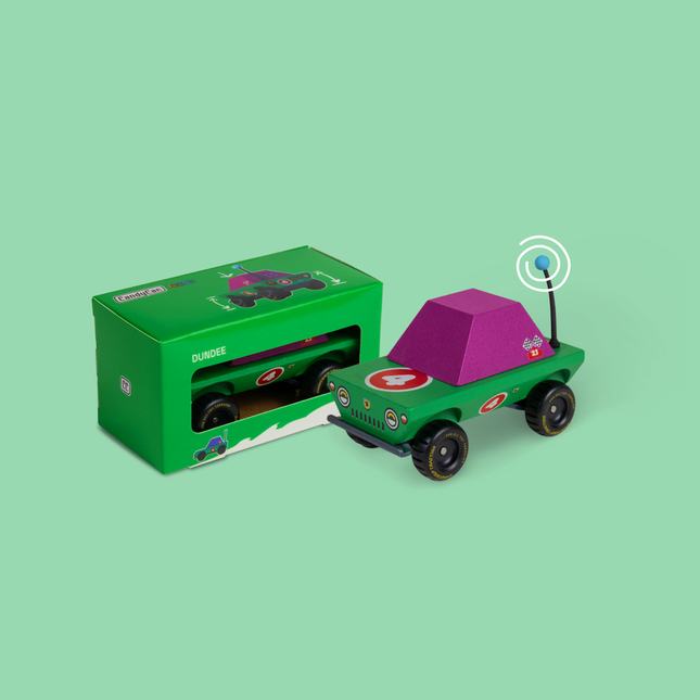 Toy car with purple roof and green body next to its packaging on a light green background