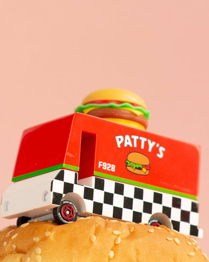 Toy truck labeled 'Patty's' with a hamburger on top of a burger bun against a pink background