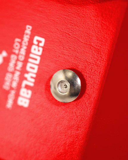 Close-up of a red object with a metallic hardware and 'CANDYLAB' branding.