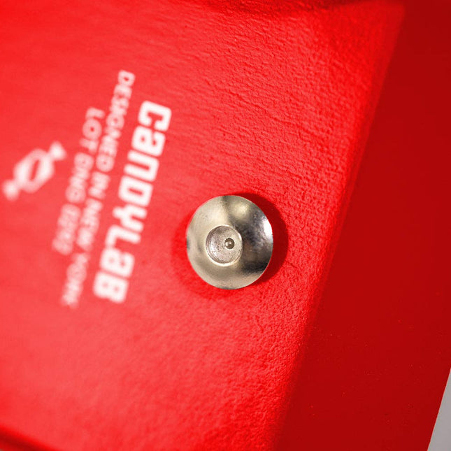 Close-up of a red object with a metallic hardware and 'CANDYLAB' branding.