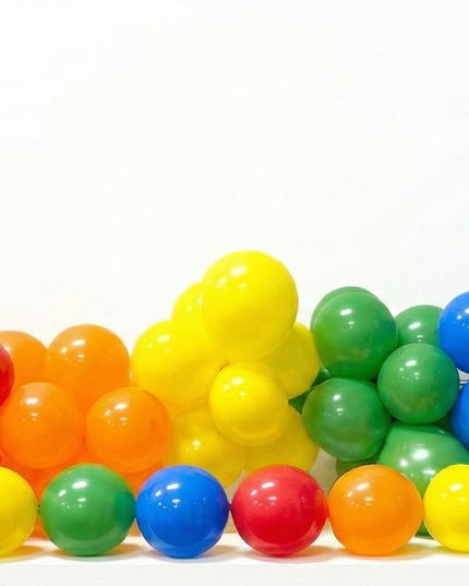 Colorful plastic balls arranged in a rainbow pattern with silver star decorations on a white background.