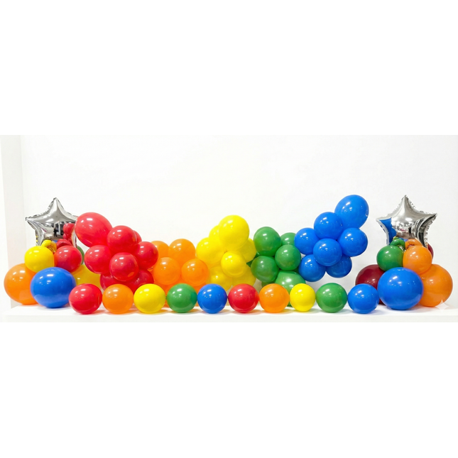 Colorful plastic balls arranged in a rainbow pattern with silver star decorations on a white background.