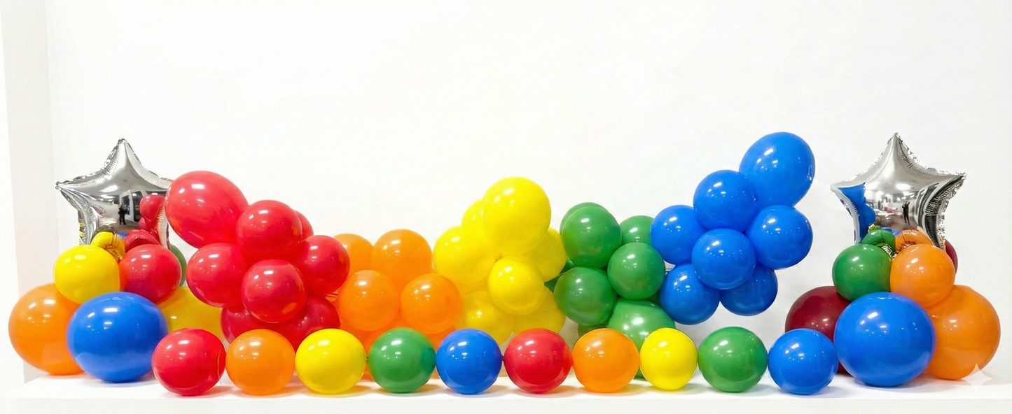 Colorful plastic balls arranged in a rainbow pattern with silver star decorations on a white background.