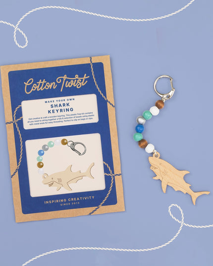 Cotton Twist shark keyring kit with wooden shark shape and colorful beads on a blue background