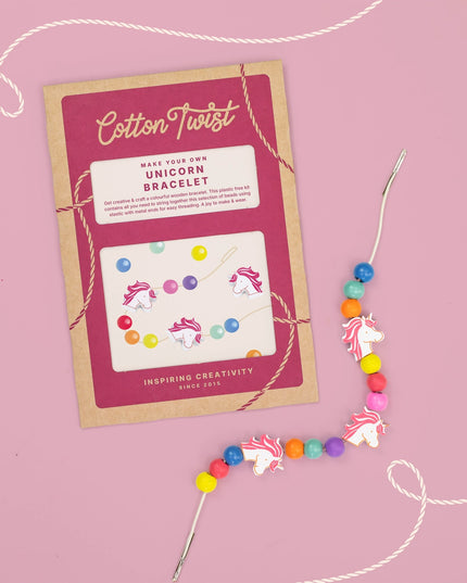 Unicorn bracelet-making kit with colorful beads and packaging on a pink background