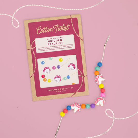 Unicorn bracelet-making kit with colorful beads and packaging on a pink background