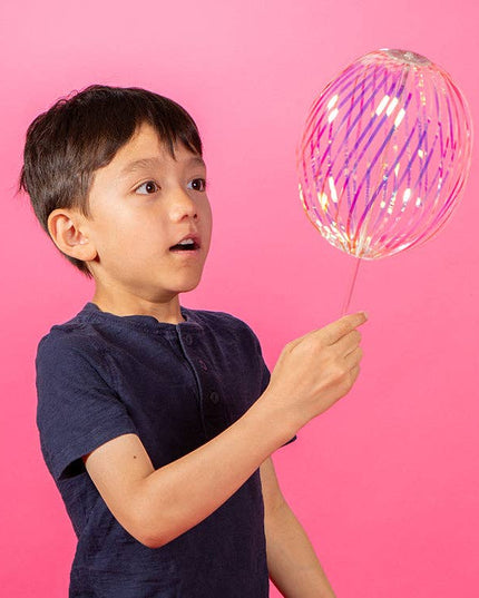 Child holding a colorful balloon against a pink background