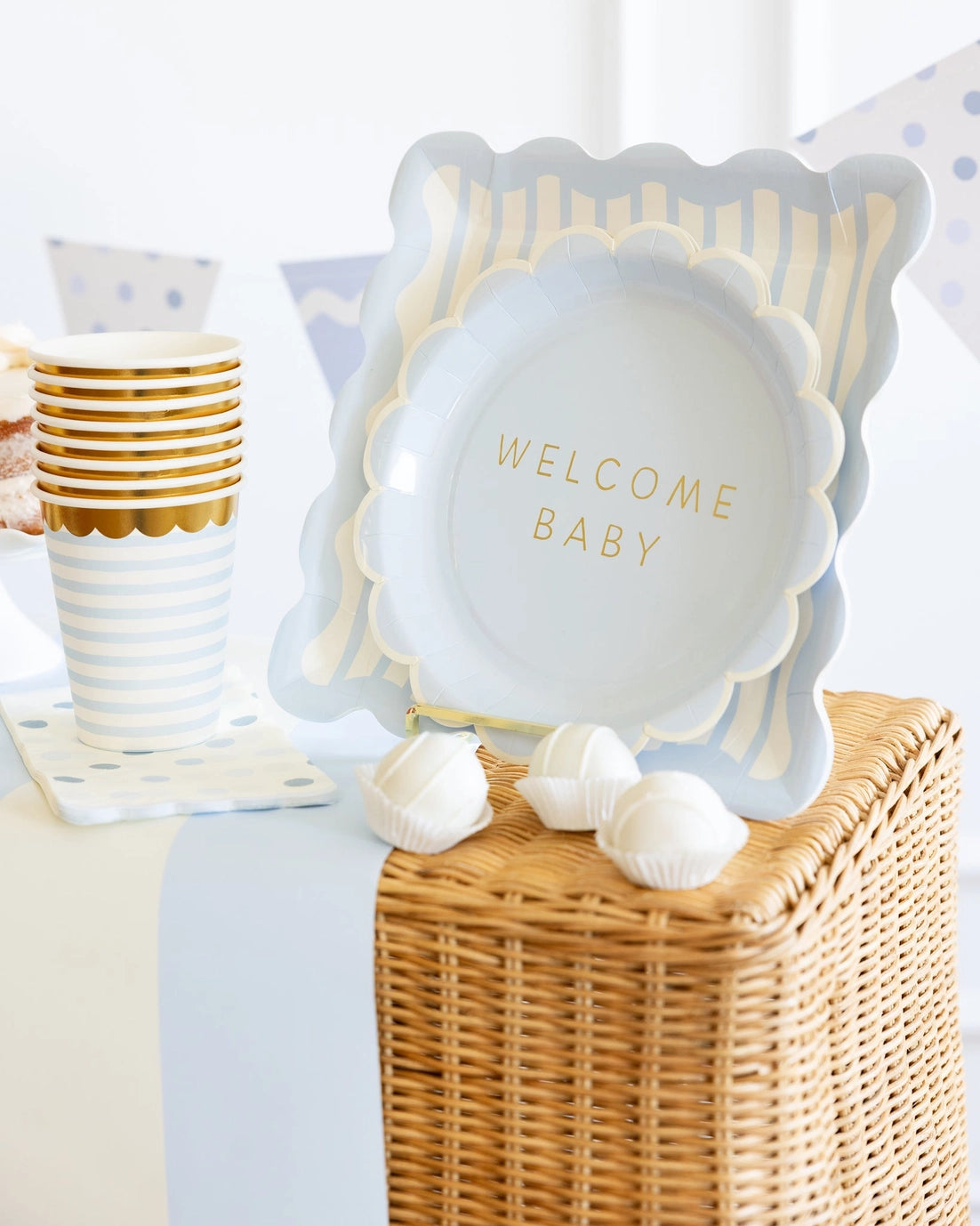 Decorative display with baby shower plate and 'Welcome Baby' text on a table with party supplies.