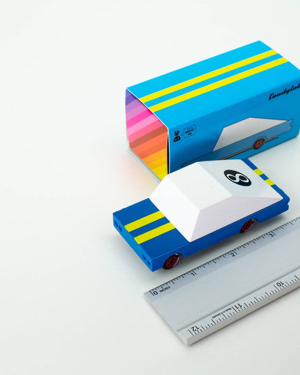 Colorful packaging box with a small car model and a ruler for scale on a white background